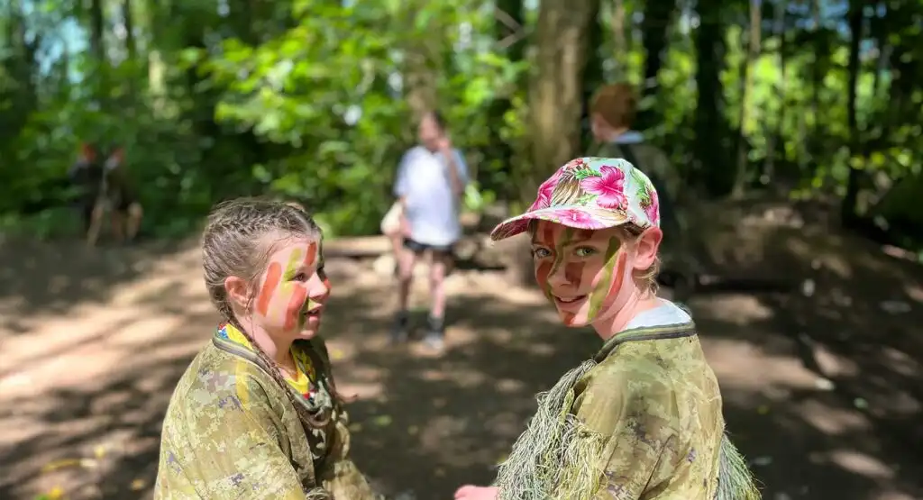 Two children wearing helmets and harnesses climbing a colorful rock wall at Fota Island Adventure, with a blue sky in the background