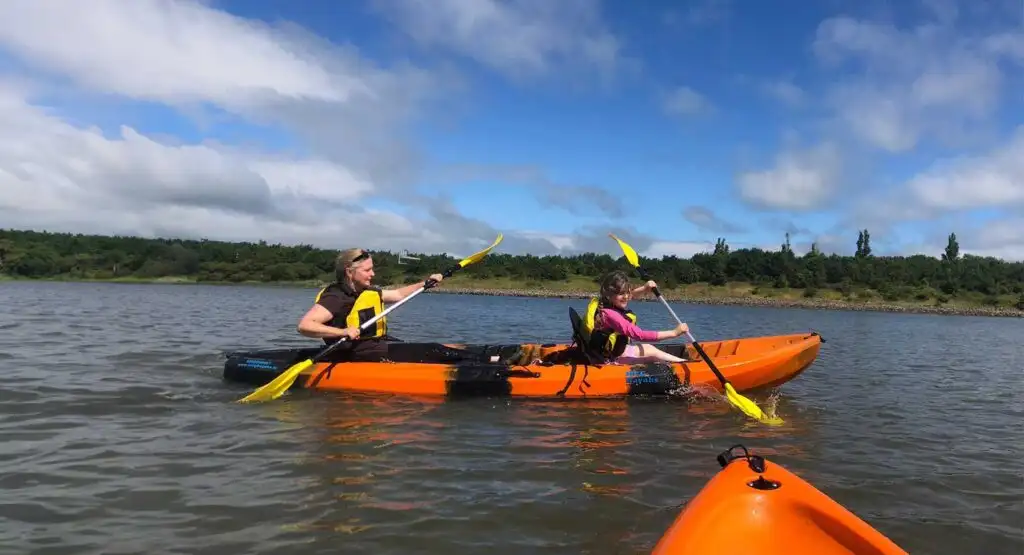 Kayakers enjoying a sunny day on the lake at Fota Island Adventure, with reflections on the water.