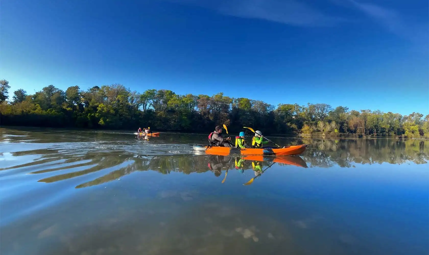 A group of people kayaking on a calm lake at Fota Island Adventure, surrounded by lush greenery.