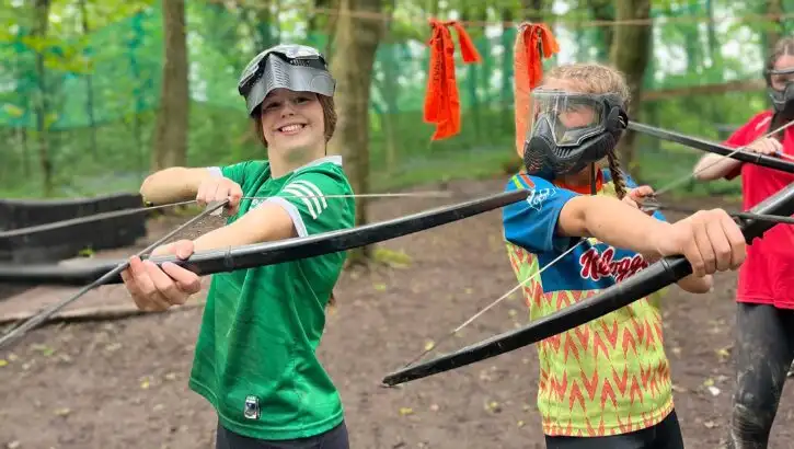 A wide-angle view of school children engaged in a team-building exercise at Fota Island Adventure, showcasing the lush surroundings and group dynamics