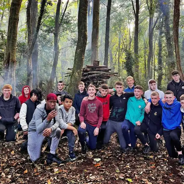 School children wearing helmets and harnesses, climbing a rock wall at Fota Island Adventure.