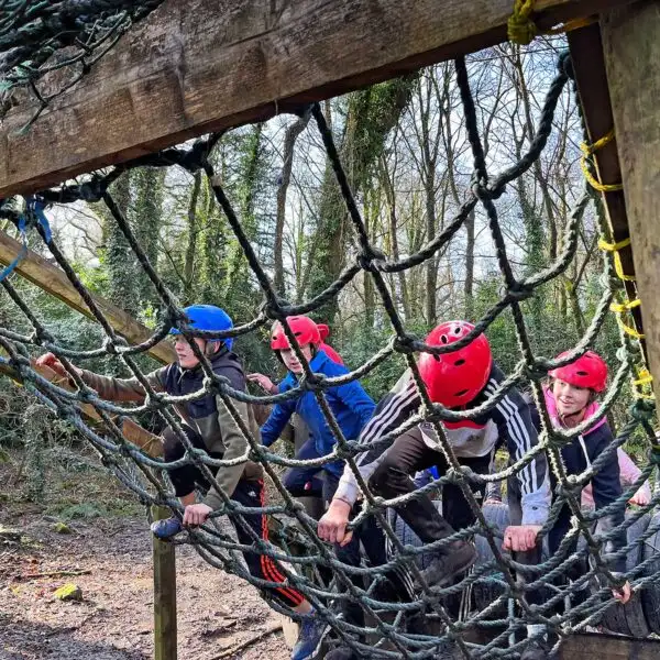 A group of students navigating an obstacle course with ropes and nets at Fota Island Adventure.