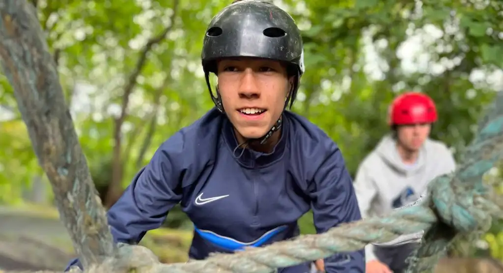 A group of colleagues participating in a team-building exercise at Fota Island Adventure, involving a ropes course challenge.