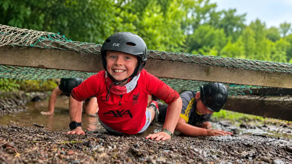 Smiling child wearing a helmet taking part in an outdoor adventure activity at Fota Adventure
